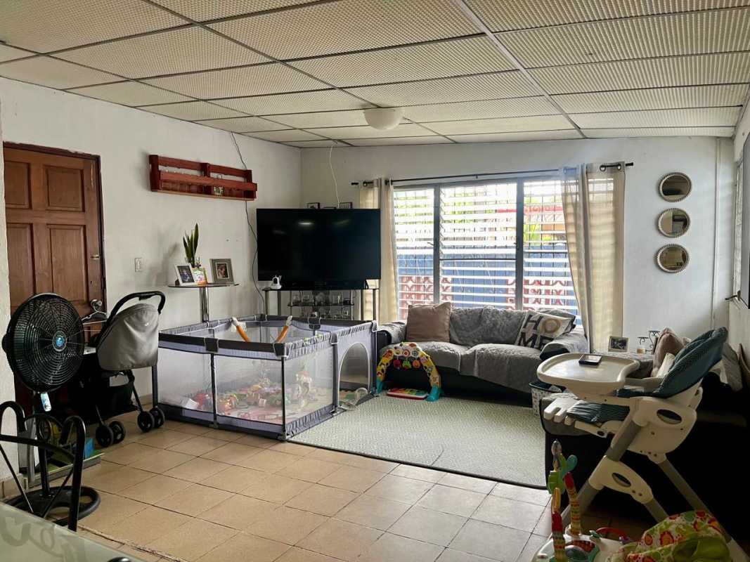Living room with two sofas, baby playpen and large windows in Villa Venus Juan Díaz