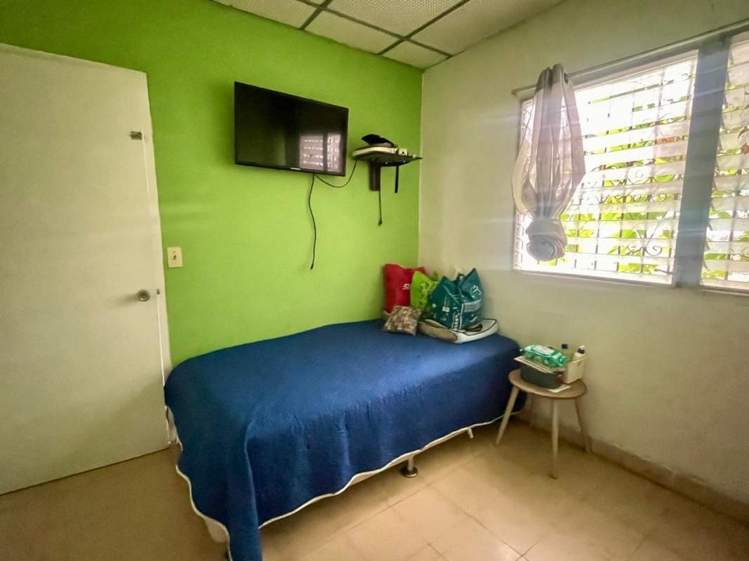 Small bedroom with a TV on wall green accent wall blue bed Villa Venus Panama