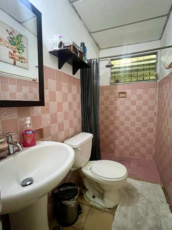 Small bathroom with pink checkered tiles pedestal sink shower Villa Venus Juan Díaz