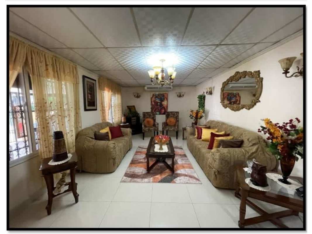 Connected dining and living space with ceiling fan, red accent wall, tile floor in family house