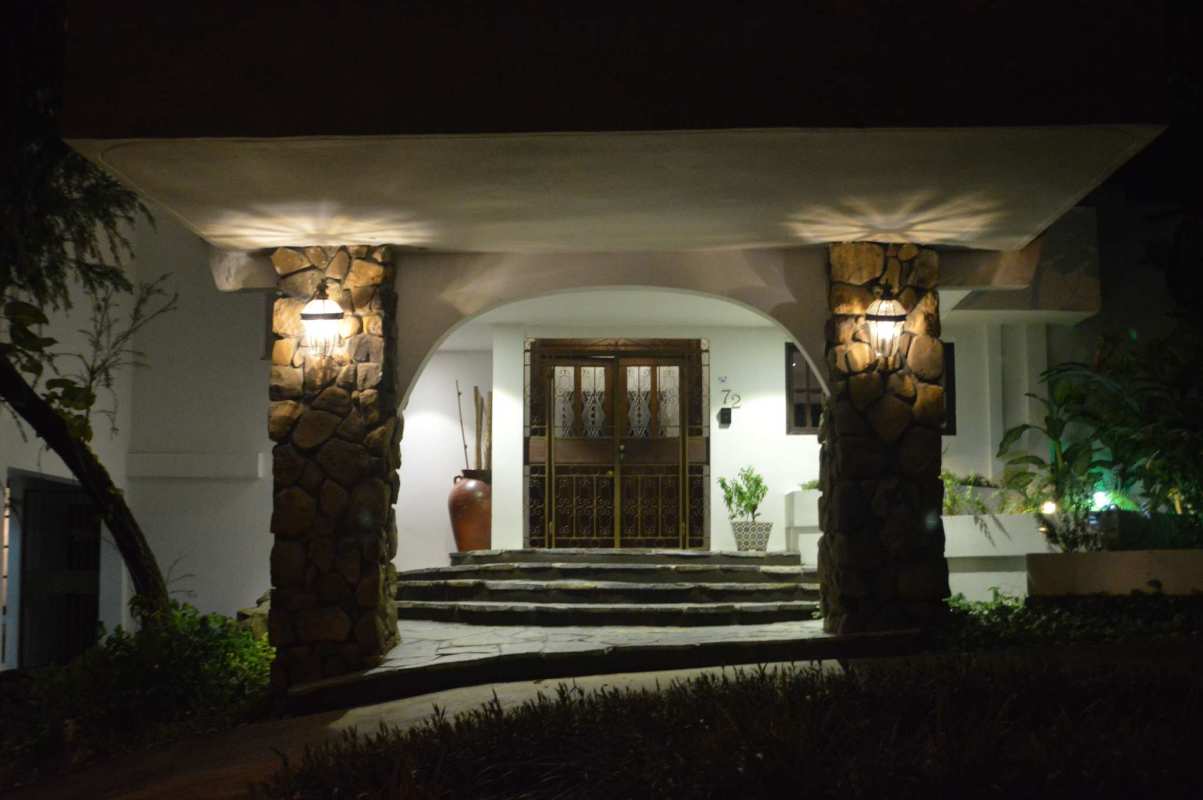 Mediterranean-style entrance with stone columns and arched double door illuminated at night at La Loma residence Panama City