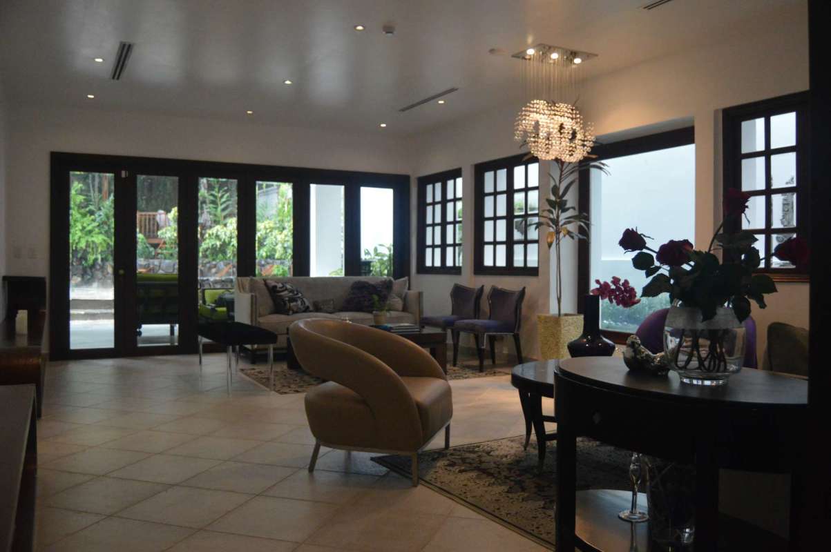 Luxury living room with large windows, modern furnishings, tile floors, garden views in La Loma house Panama City