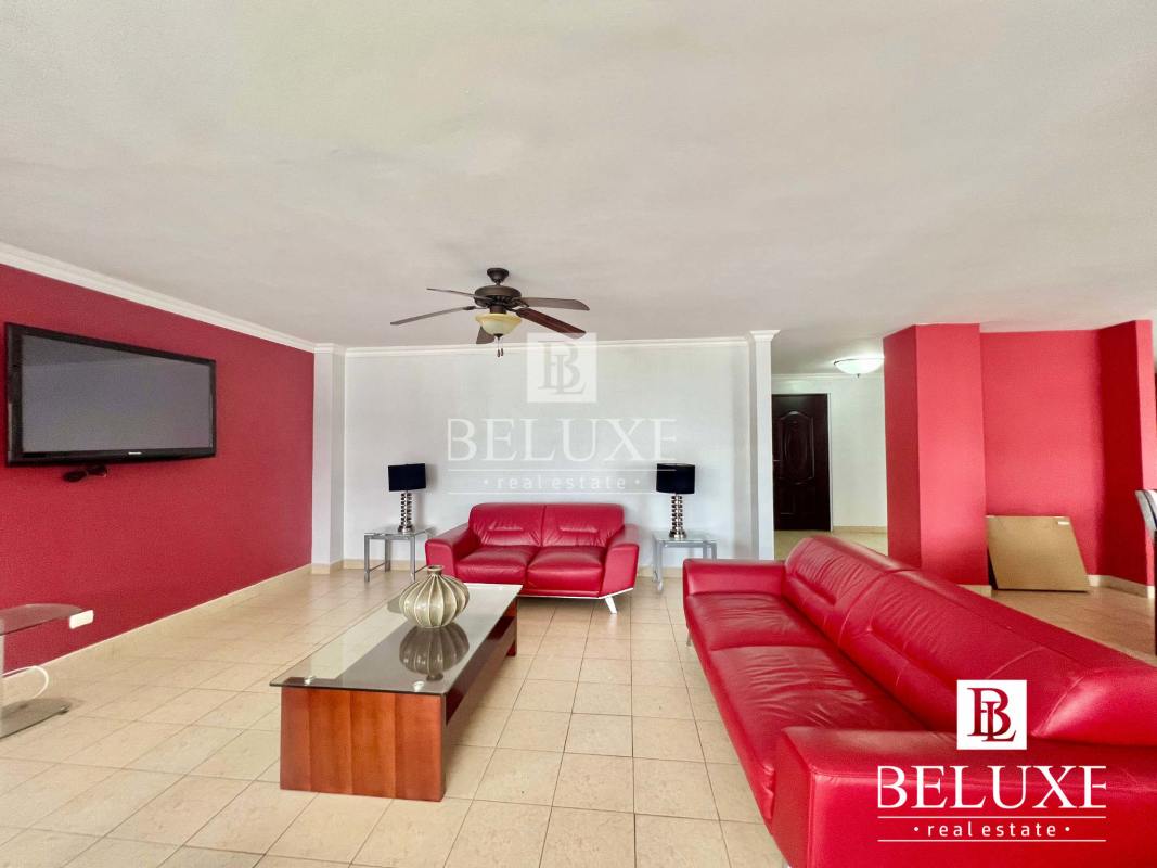 Furnished living room with red accent walls, tile floors, TV and ceiling fan PH Don Camilo Panama City