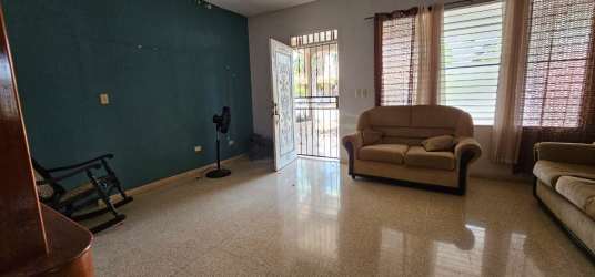 Living room featuring green accent wall, large windows, and natural light in El Vigía home