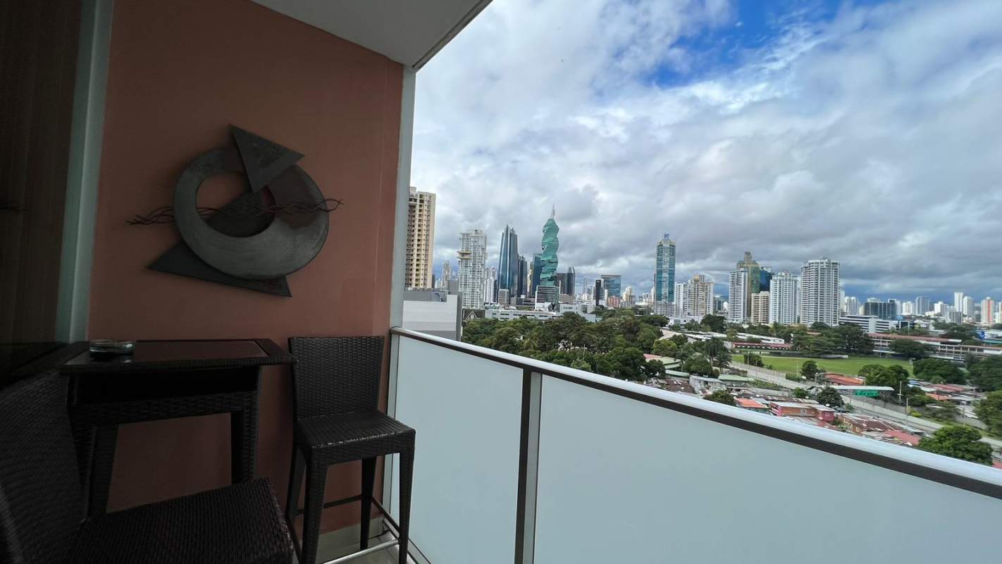 Open concept living-dining with sectional sofa, stone wall and city views at PH Pacific Sun Panama