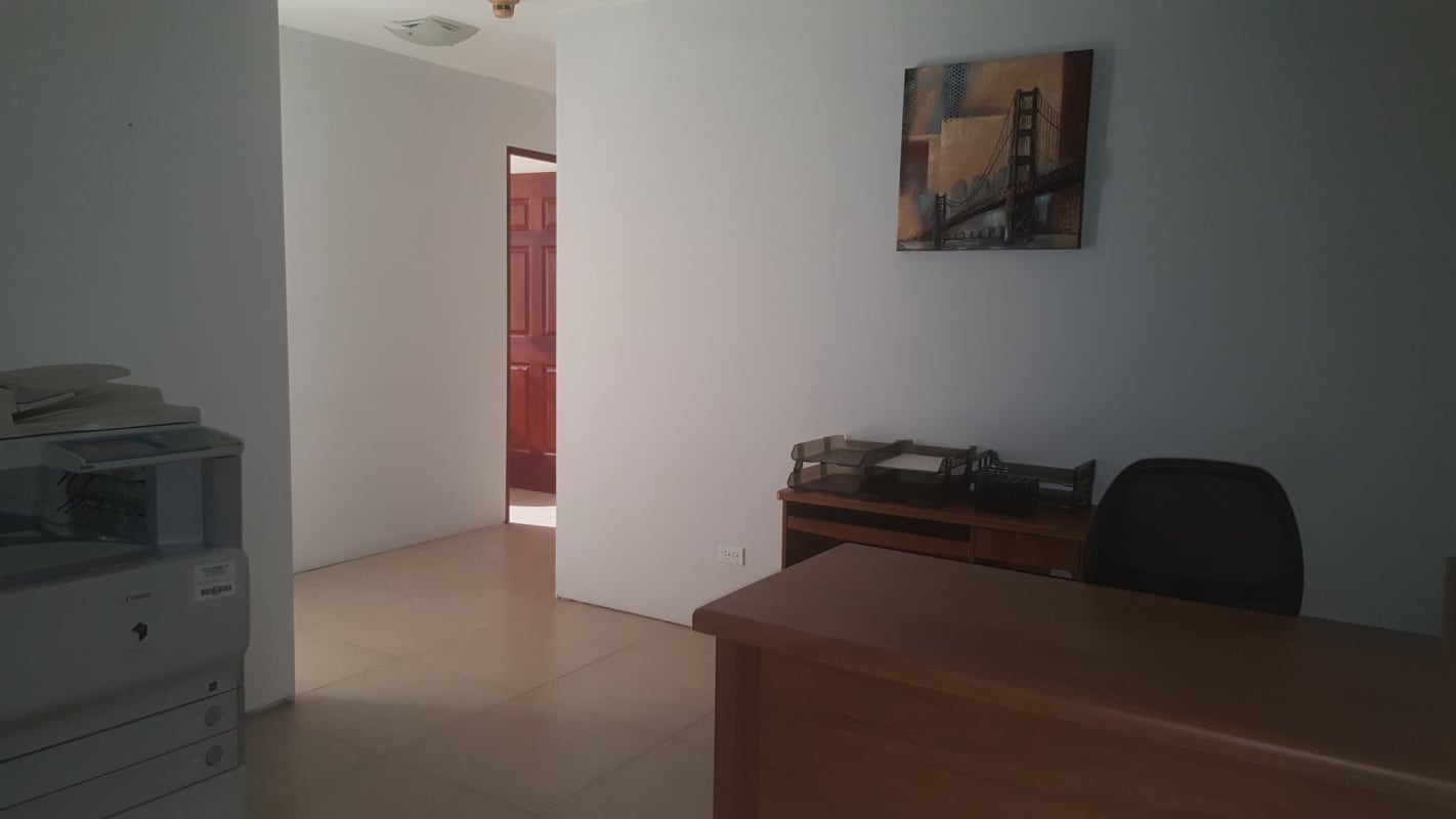 Office lobby with wooden desk, document trays, printer, wall art at PH Obarrio Tower Panama City