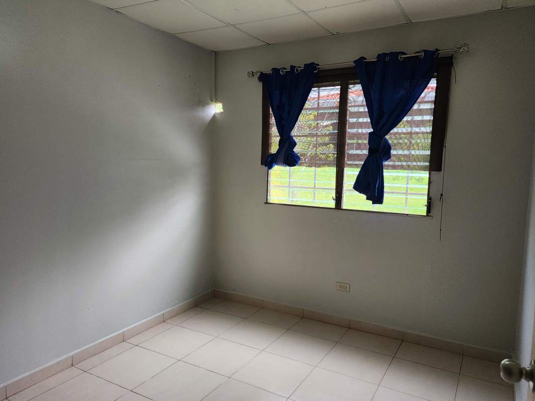Small bedroom with gray walls, tiled floor, wall shelf and window in Brisas del Lago Panama City