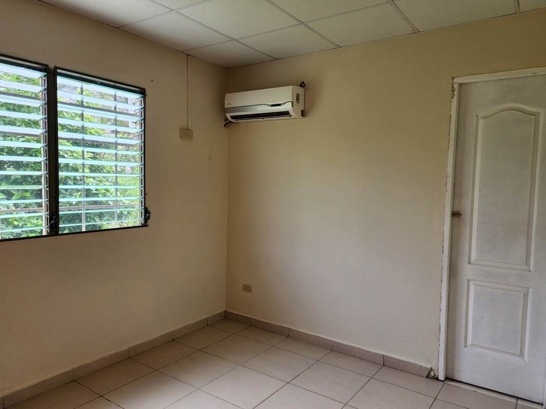 Bedroom with split AC, louvered window and beige walls in Las Cumbres Panama