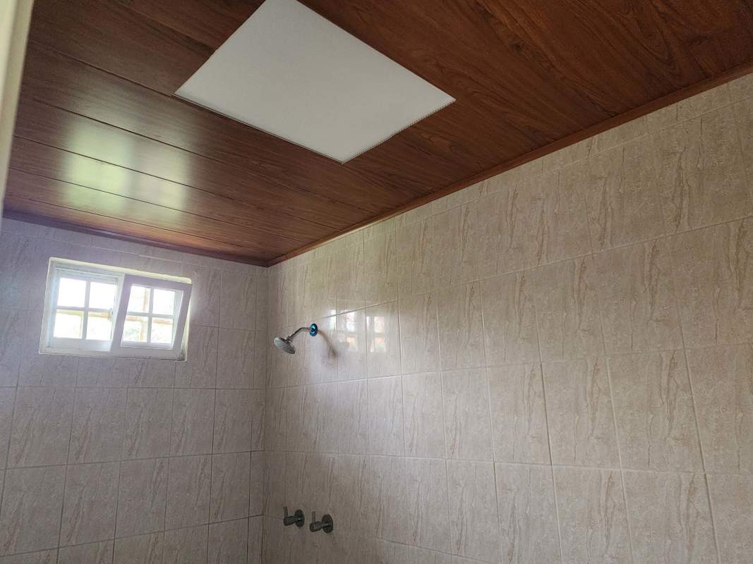 Small bathroom with pedestal sink, shower space and beige tiles in Brisas del Lago