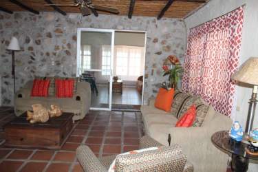 Cozy living room with stone feature wall, tile floors and wood beams in Gorgona beachfront villa