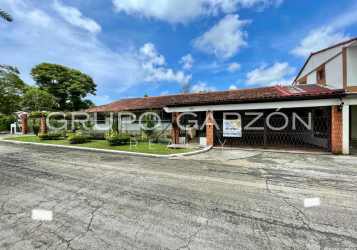 Covered carport and driveway with green garden and tiled roof at family house Howard Panama Pacifico