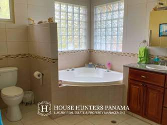 Spacious bathroom with corner jacuzzi tub, glass block windows, tiled walls and vanity in house Portobelo Panama