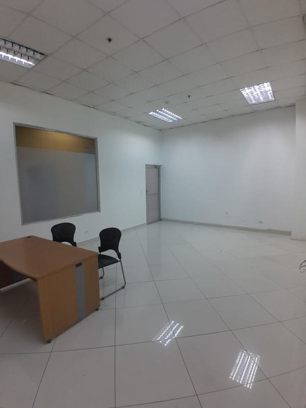 Office room with tiled floor, wooden desk, black chairs, fluorescent lights Plaza Tocumen Panama