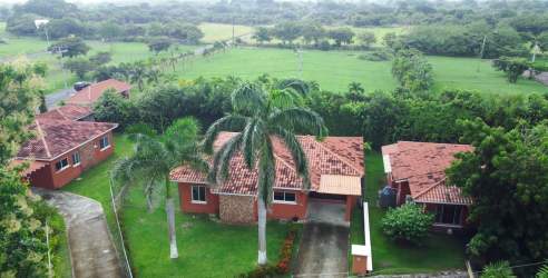 Mediterranean single-story beach house with red tile roof, garden and carport at Villas de la Colonia Chame Panama