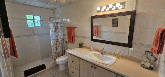 Spacious kitchen with white cabinetry, granite countertops, large island and garden views in Cabuya Chame home