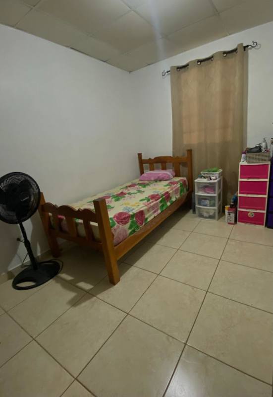 Bedroom with tiled floor, single bed, plastic storage drawers, and window in Los Álamos Pacora Panama