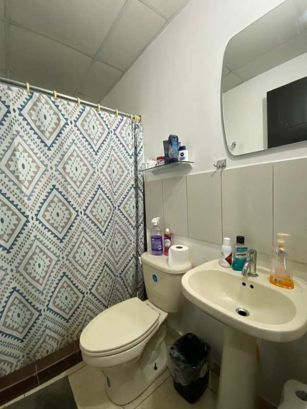 Small bathroom with pedestal sink, shower curtain, and tiled walls Los Álamos Pacora Panama
