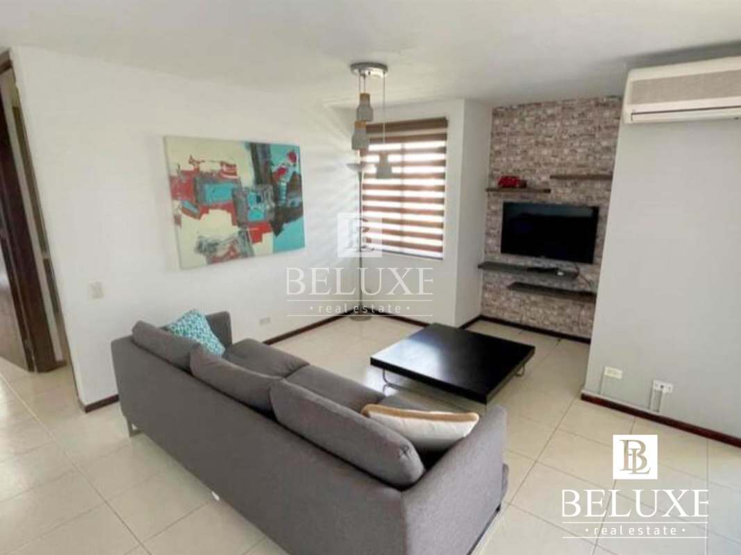 Spacious living room with stone wall accent, mounted TV and sectional sofa PH Pacific Wind Panama