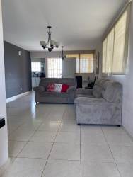 Ample living area with gray sofa, tiled floor, connected to kitchen in Colinas del Sol house