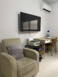 Living room with work station, beige armchair, wall-mounted TV in house Colinas del Sol Panama