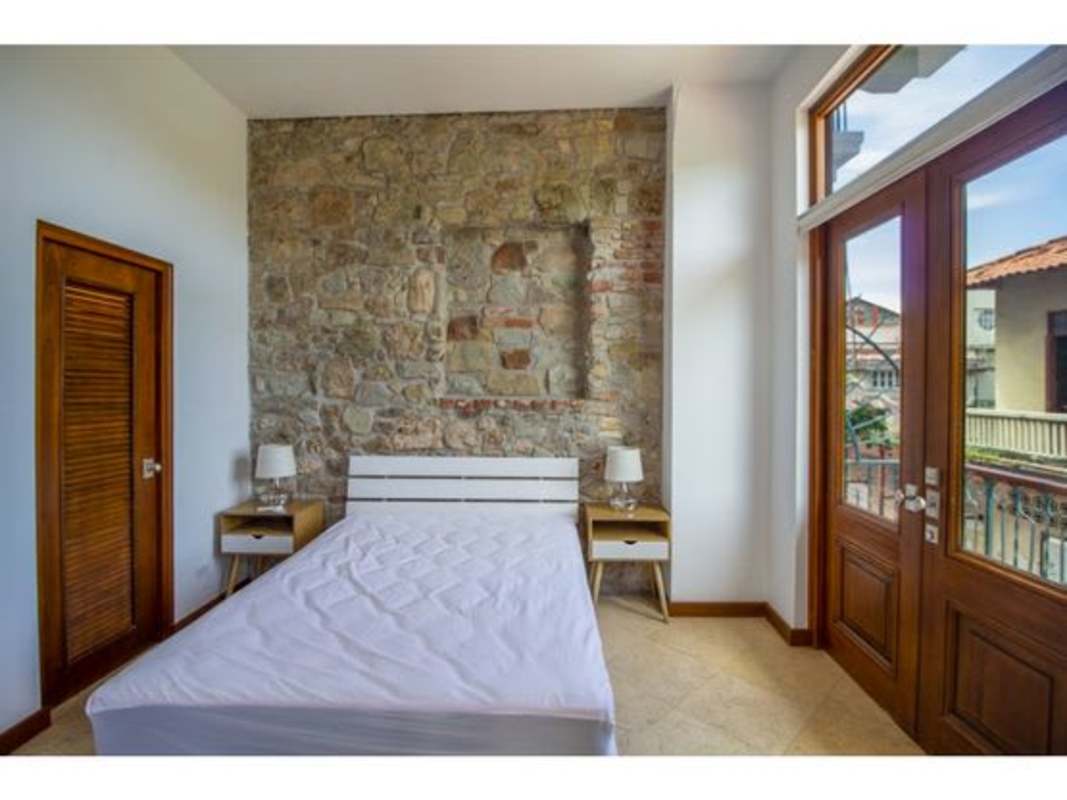 Rustic contemporary bedroom with exposed stone wall, balcony doors PH Puerta de Mar