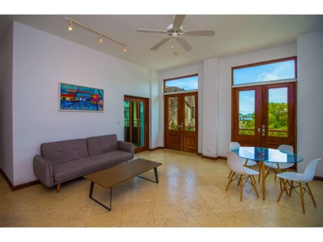 Spacious living room with stone walls, wood doors, natural light PH Puerta de Mar Casco Viejo
