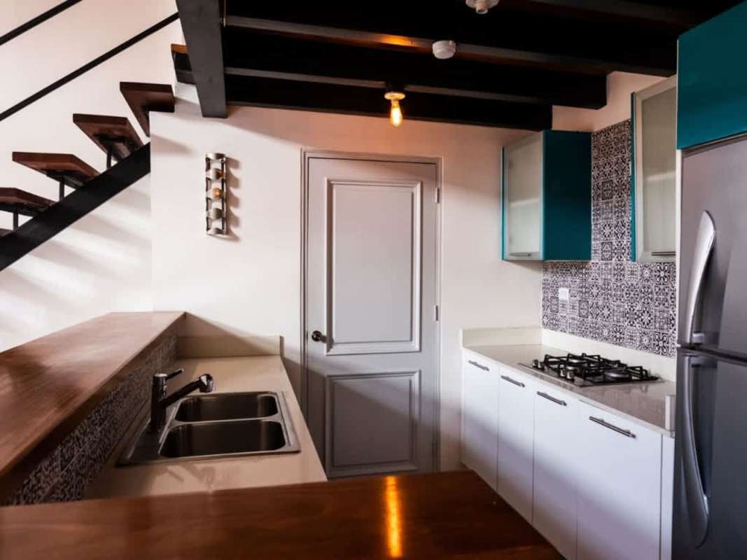 Industrial kitchen with wooden countertop, tile backsplash, floating staircase in Casco Viejo apartment for sale