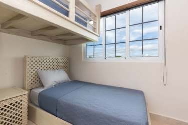 Minimalist kid's bedroom with bunk beds, blue bedding and large window at Bijao luxury beach house