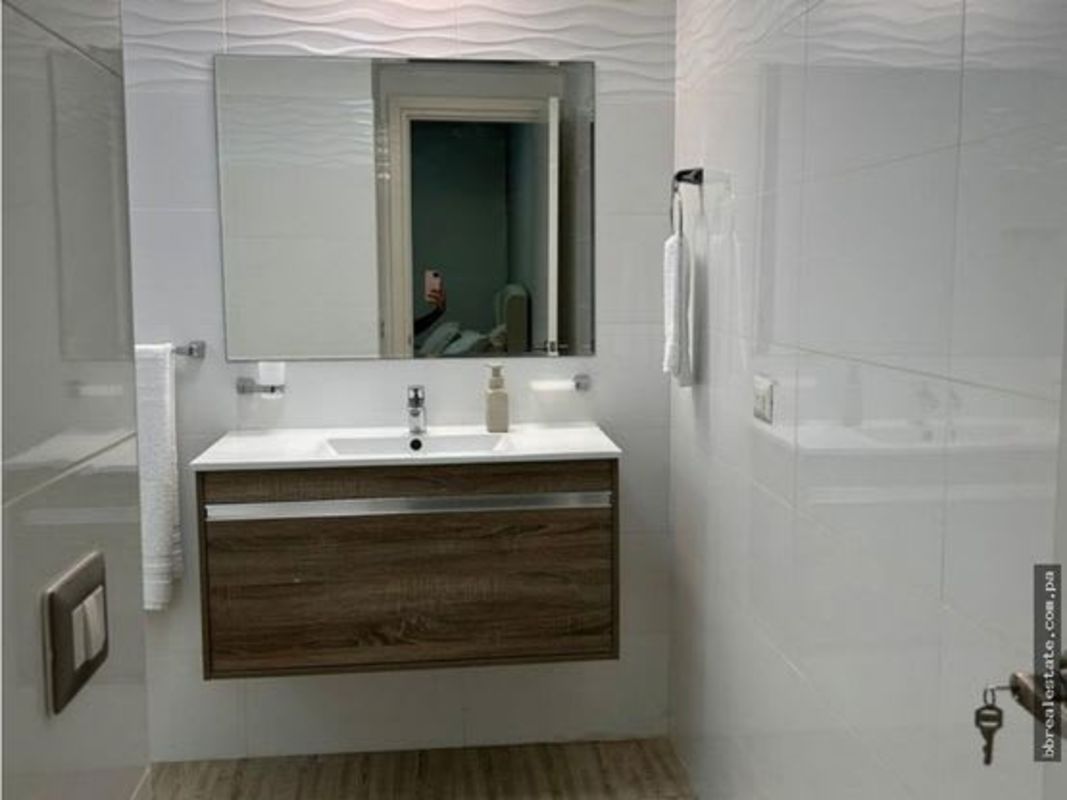 Living area with mounted TV, beige sofa, coffee table, floor-to-ceiling windows in PH Quartier Atlapa Panama