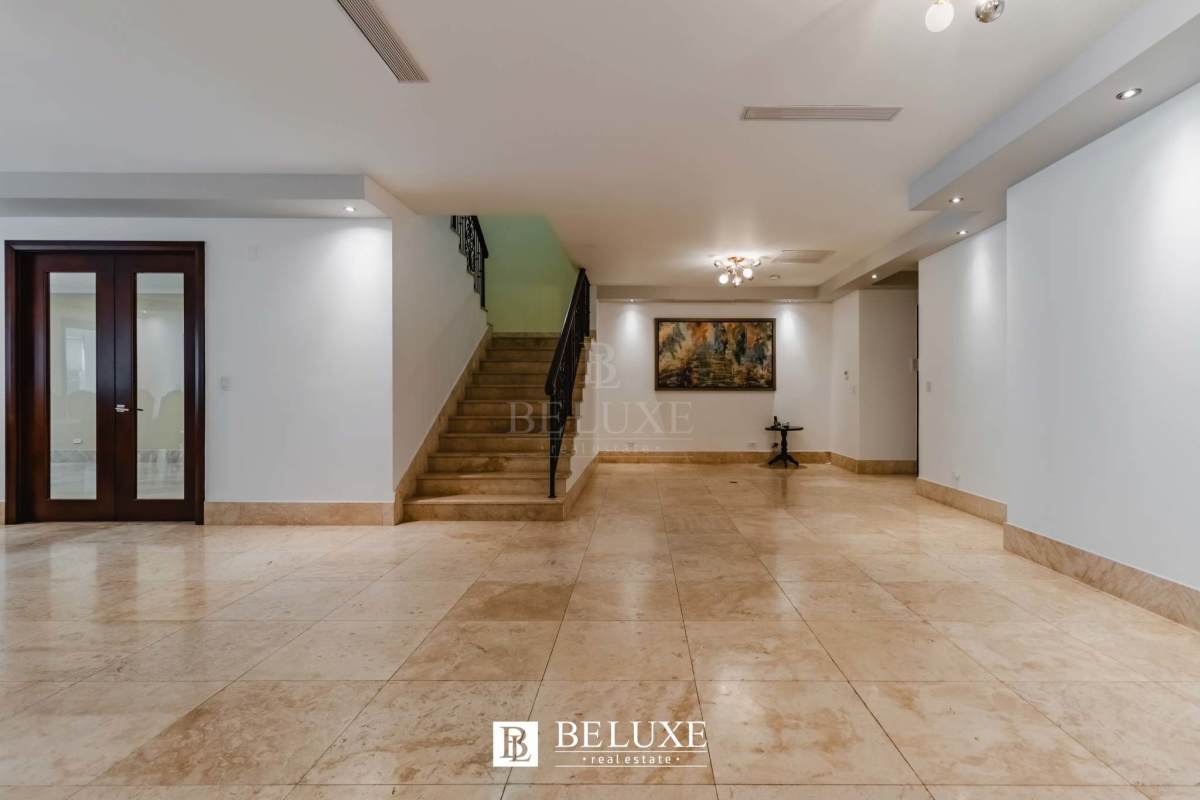 Grand entryway with marble flooring, iron staircase, glass doors and accent lighting in Santa María luxury villa for rent