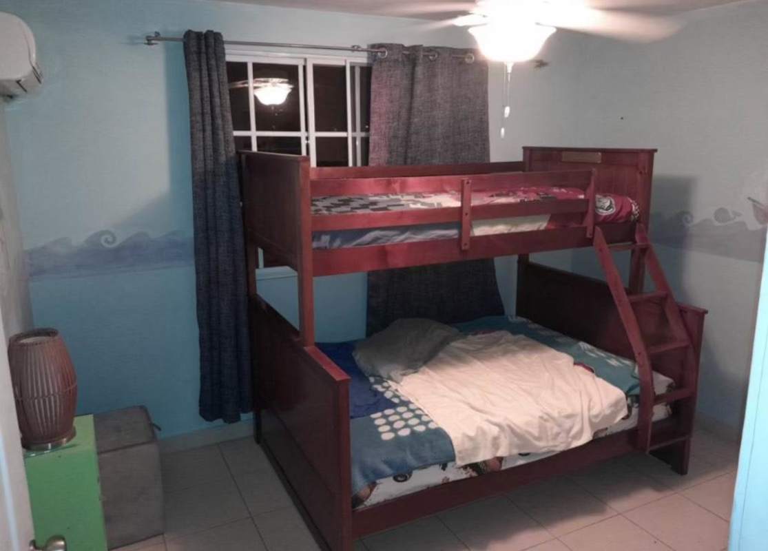 Bedroom with dark wood bunk bed, curtain window, fan, AC in Dorado Springs Condado del Rey