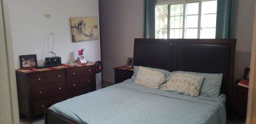 Bedroom with large window, curtains, and wood dresser in Gorgona beach house Panama
