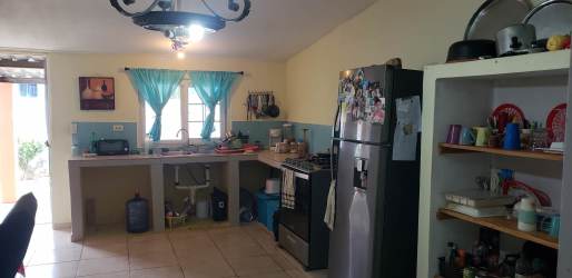 Kitchen with light blue accents, open shelves, gas stove, refrigerator, window with blue curtains in Gorgona beach house