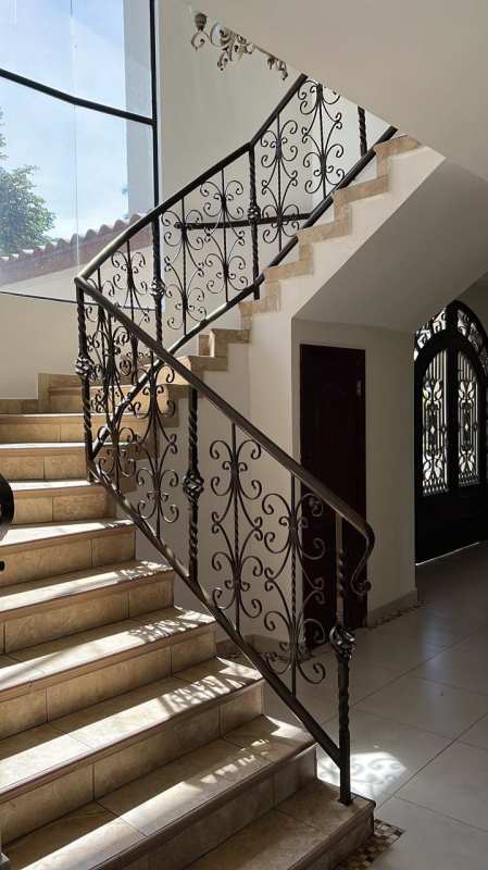 Interior staircase with wrought iron railing and large window Panama City house