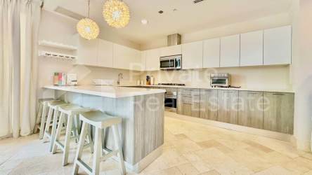Luxury kitchen with white cabinetry island stainless appliances in Buenaventura condo for sale Panama