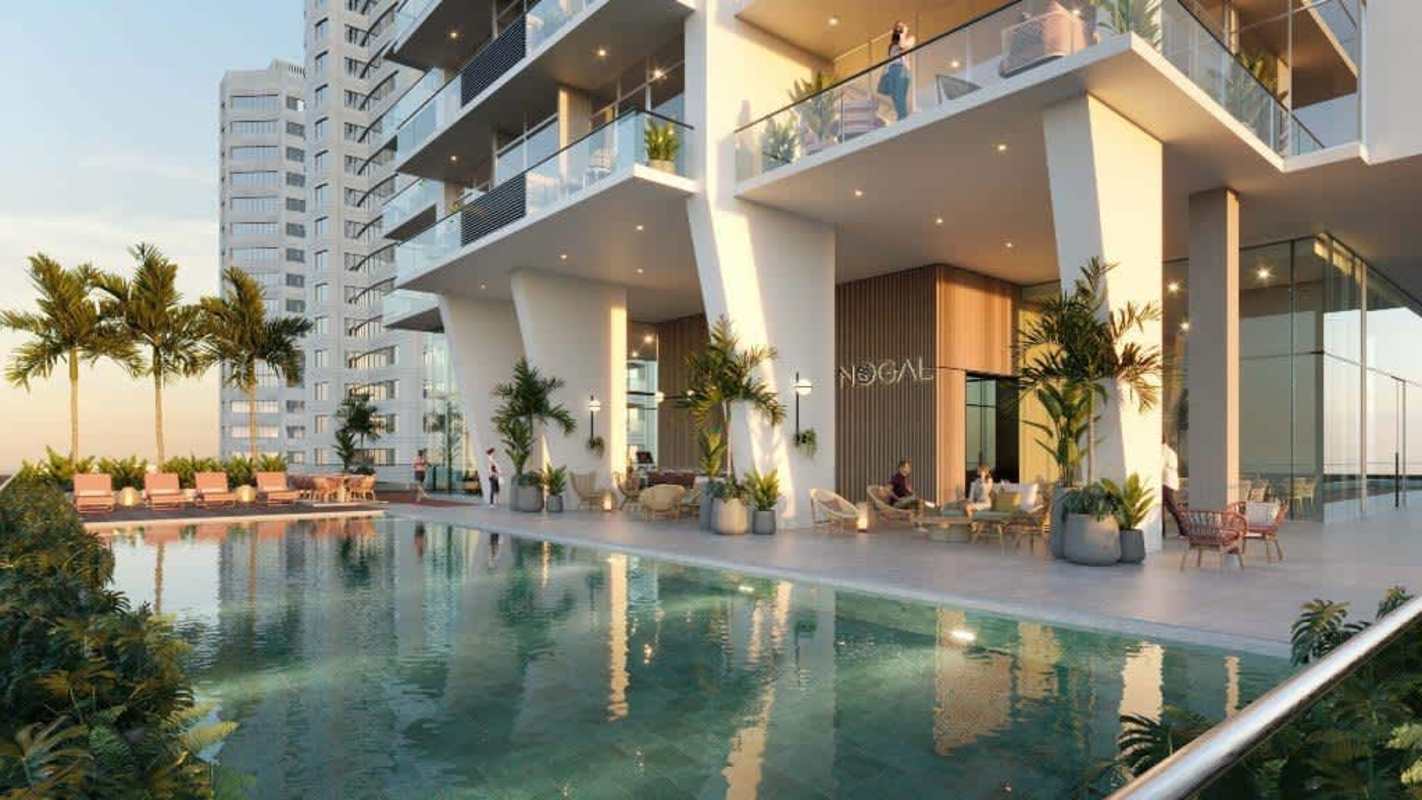 Tall luxury condo tower with balconies, palm trees entrance and glass facade at Costa del Este Panama
