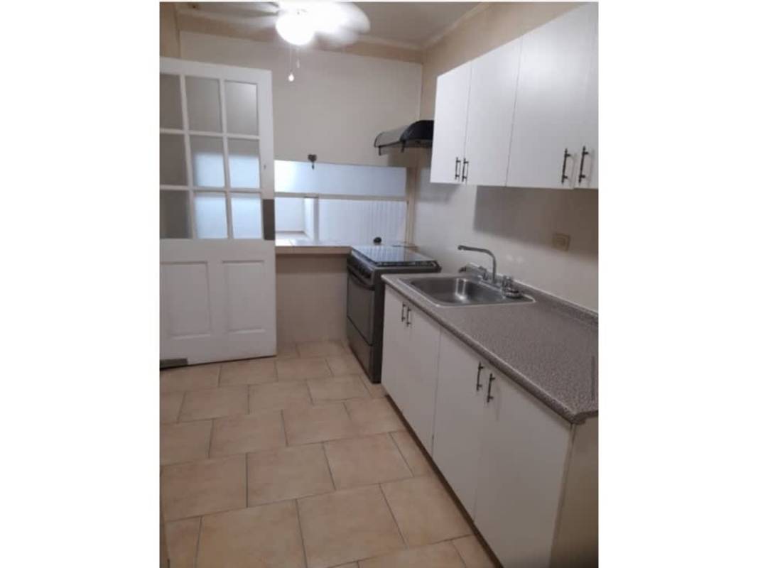 Galley kitchen with white cabinets and breakfast bar pass-through in apartment for sale Betania Panama