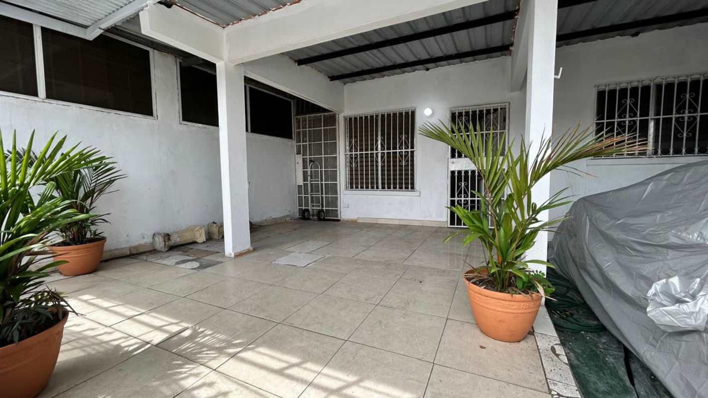 Narrow hallway with tiled floor and windows with security bars in family house Las Mañanitas