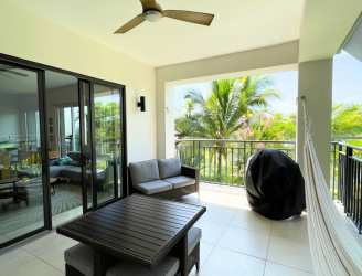 Open modern kitchen with white cabinetry, breakfast bar, microwave, stainless appliances in Buenaventura condo