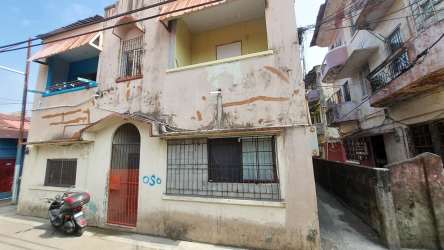 Two-story residential commercial complex with iron bars, balconies and scooter parked out front in Colon Panama