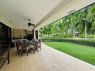 Covered patio area with outdoor kitchen, dining table, ceiling fan and garden views in Buenaventura Panama