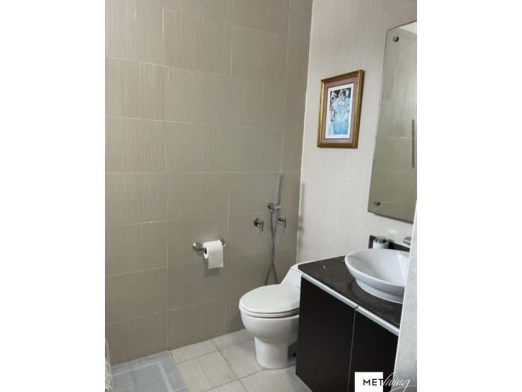 Modern bathroom with wall-mounted toilet, vessel sink on vanity, framed artwork, beige tiles at PH Luxor El Cangrejo