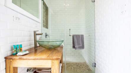 Rustic modern bathroom with wood cabinetry, vessel sink and glass shower in Blue Venao