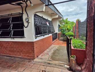 Traditional home facade with red brick trim, iron security bars and garden walkway in Colón Panama for sale