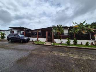 Exterior of house with palm trees, gated yard and driveway in Colón Panama for sale
