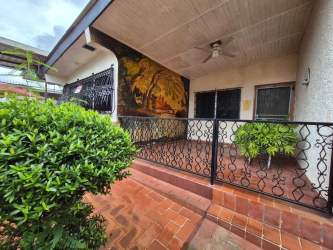 Front covered porch with mural, ironwork, and garden in Colón Panama property