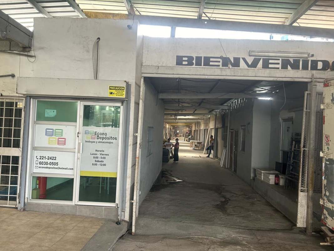 Exterior covered walkway of industrial warehouse complex with signage and secure units in Panama City