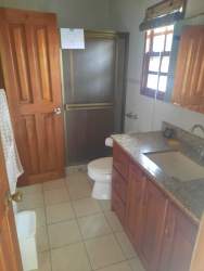 Traditional kitchen with brick island, wooden cabinets, and tile floor in Cuesta del Sol condo David Panama