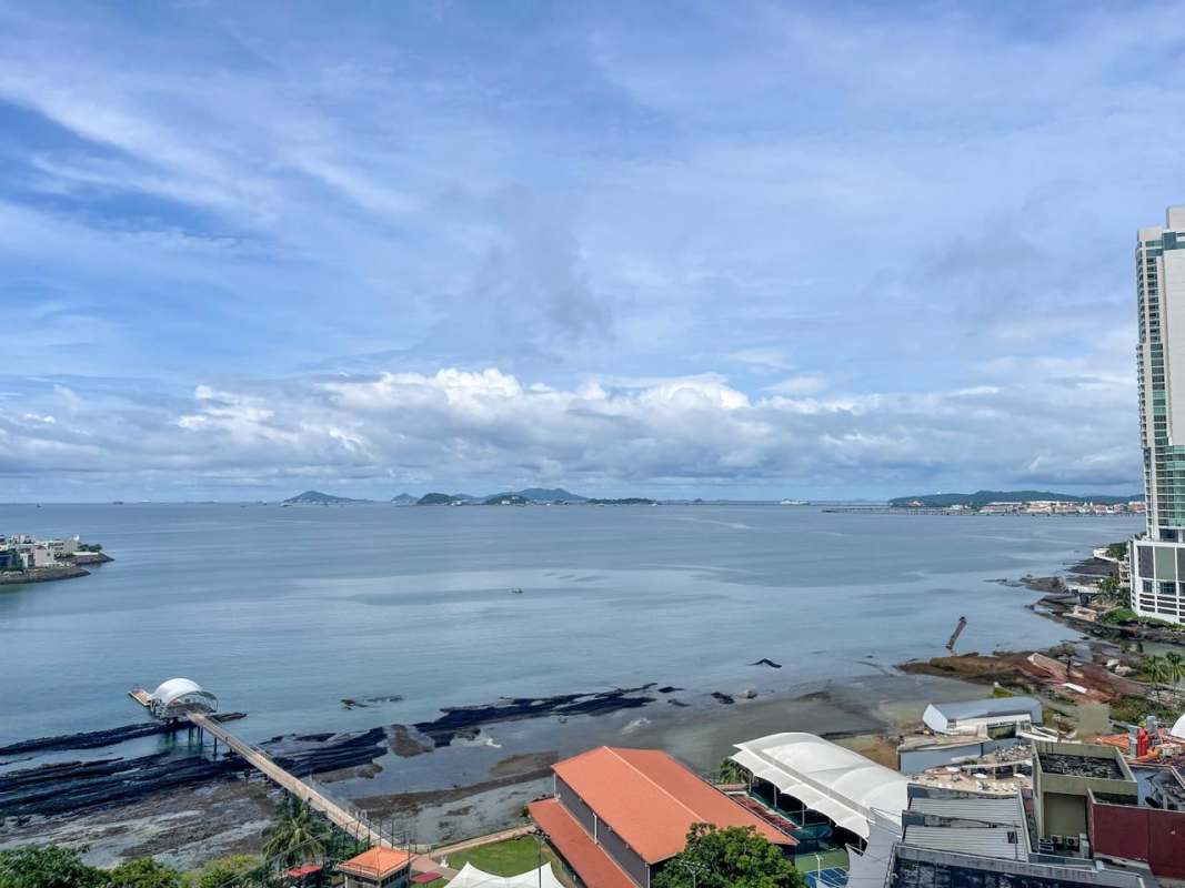 Infinity pool overlooking Pacific Ocean with lounge chairs and palm trees PH Q Tower Punta Pacífica