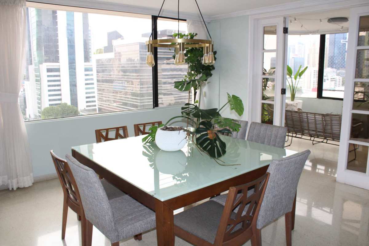 Dining area with glass table, large windows and city skyline views in Obarrio Panama apartment